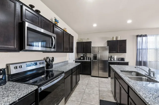 a kitchen with stainless steel appliances granite countertop a sink and a refrigerator
