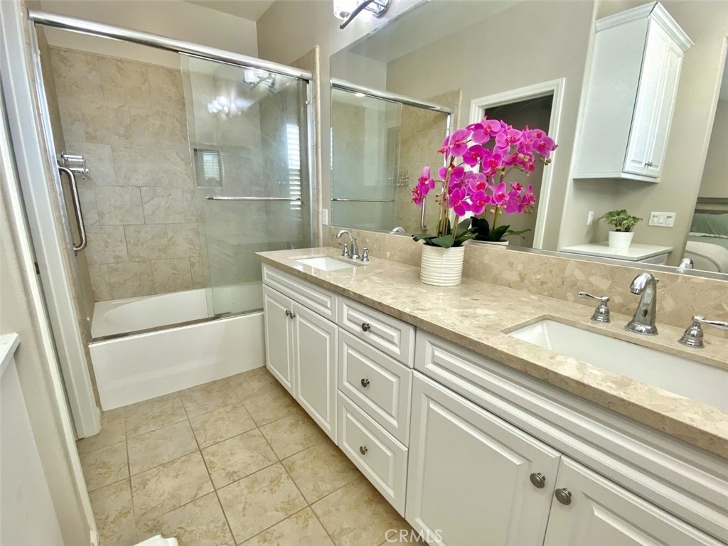 44011 Rivo Court Temecula, CA 92592 - Photo 22 of 39 a bathroom with a granite countertop sink a shower and a mirror