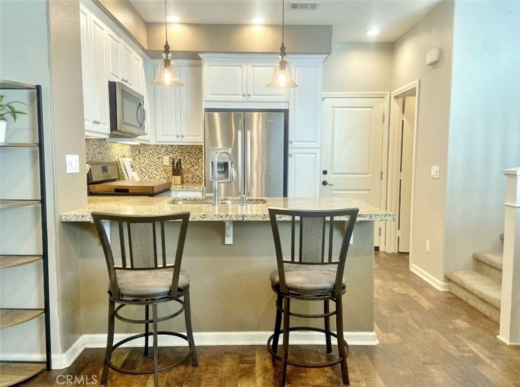44011 Rivo Court Temecula, CA 92592 - Photo 6 of 39 a kitchen with stainless steel appliances granite countertop a dining table chairs and a refrigerator