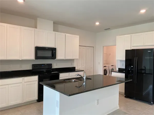 a kitchen with granite countertop a sink a counter space stainless steel appliances and cabinets