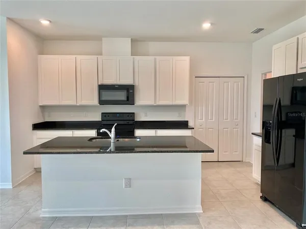 a kitchen with kitchen island granite countertop a sink stove and refrigerator