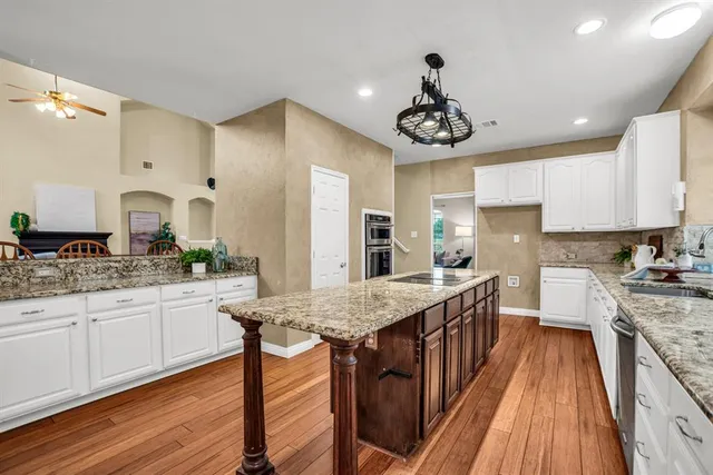 a kitchen with granite countertop a sink a counter space stainless steel appliances and cabinets