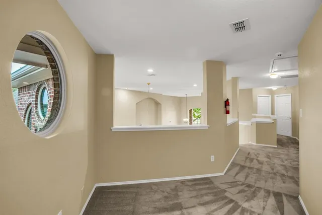 a view of a hallway with wooden floor and a bathroom