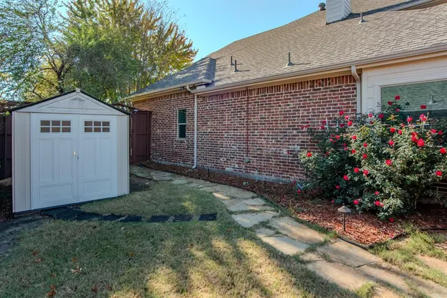 a view of a backyard with plants and brick wall