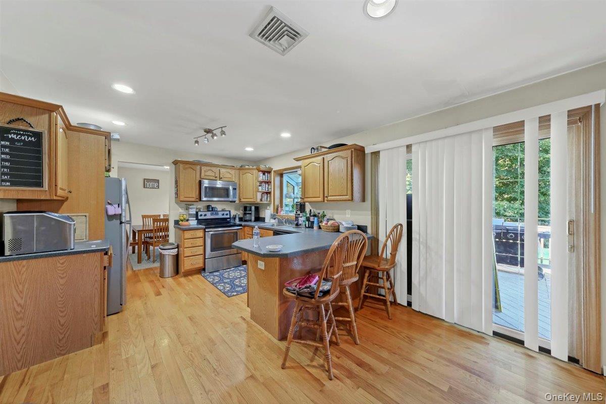 220 Prospect Road Monroe, NY 10950 - Photo 17 of 42 Kitchen with dark countertops, appliances with stainless steel finishes, a peninsula, light wood-type flooring, and a kitchen bar