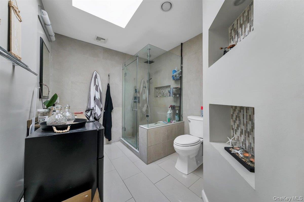 220 Prospect Road Monroe, NY 10950 - Photo 25 of 42 Full bath featuring a shower stall, light tile patterned floors, tile walls, and a skylight