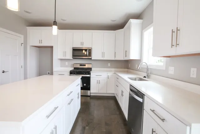 a kitchen with kitchen island granite countertop a sink a counter top space stainless steel appliances and cabinets