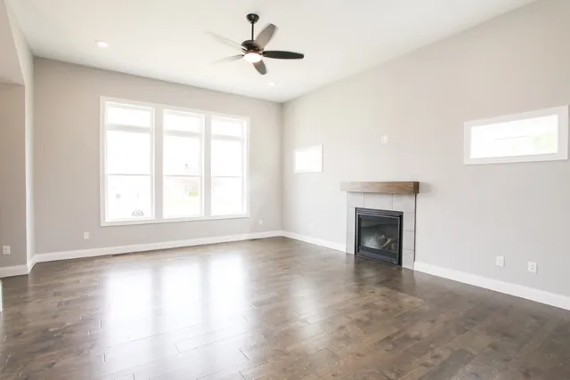 an empty room with wooden floor fireplace and windows