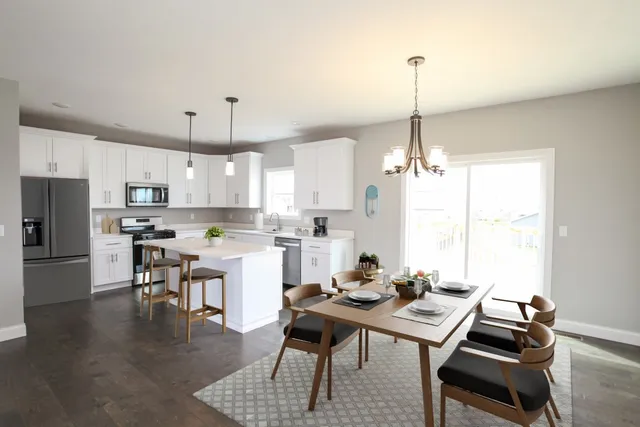 a living room with stainless steel appliances kitchen island granite countertop a stove a sink a dining table and chairs with wooden floor