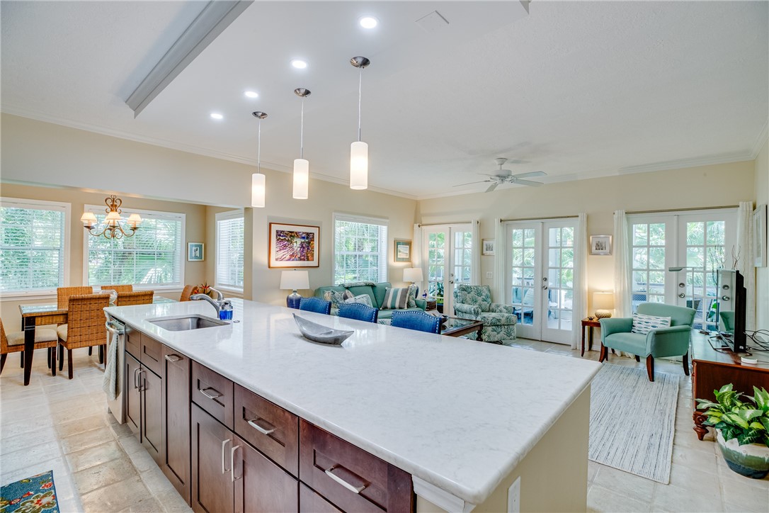 a large dining hall with stainless steel appliances kitchen island granite countertop a large kitchen island a stove a sink a dining table and chairs with wooden floor