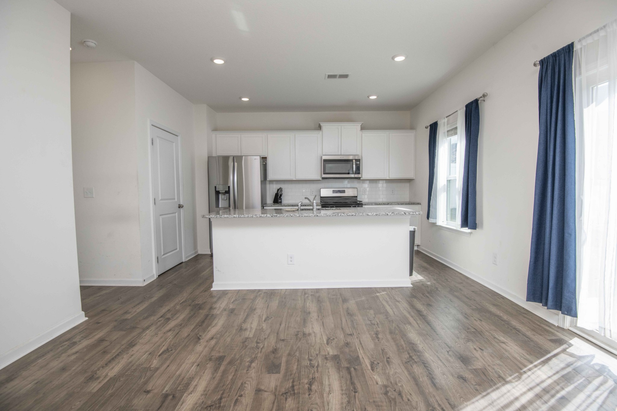514 Cliff Street Morristown, TN 37814 - Photo 7 of 45 a large white kitchen with kitchen island a sink wooden floor and a refrigerator