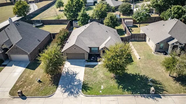 an aerial view of a residential houses with outdoor space and trees