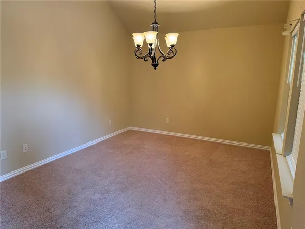 an empty room with a chandelier fan and windows