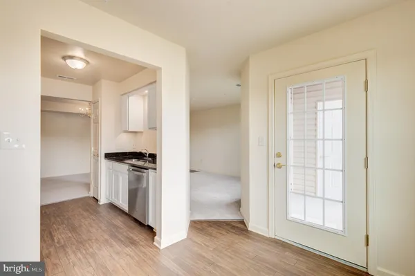 an empty room with wooden floor cabinet and windows
