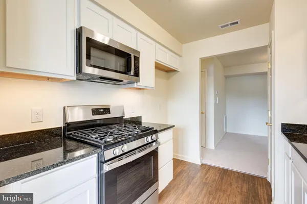 a kitchen with stainless steel appliances a white cabinet and a stove top oven