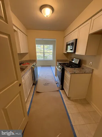 a kitchen with stainless steel appliances a refrigerator a sink a stove top oven a counter space and cabinets