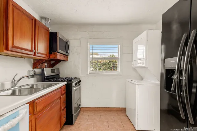 a kitchen with stainless steel appliances granite countertop a refrigerator a sink a stove a washer and dryer