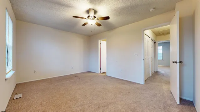 an empty room with chandelier fan and windows