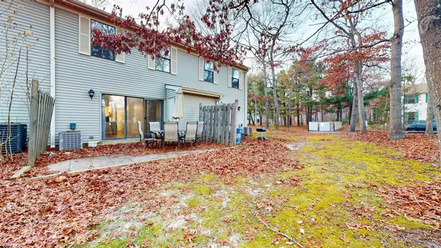 a backyard of a house with large trees and outdoor seating