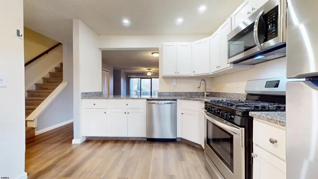 a kitchen with stainless steel appliances white cabinets and a stove top oven