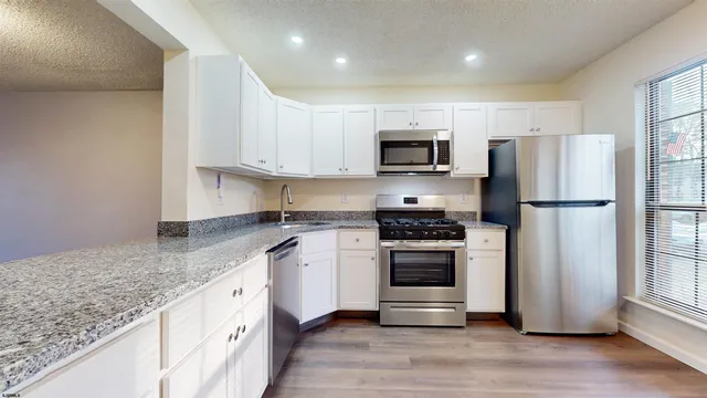 a kitchen with kitchen island granite countertop a refrigerator stove top oven and sink