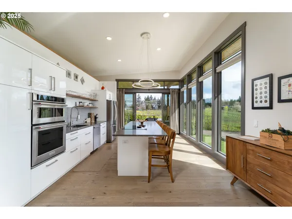 a kitchen with stainless steel appliances kitchen island granite countertop a table chairs in it and wooden floors