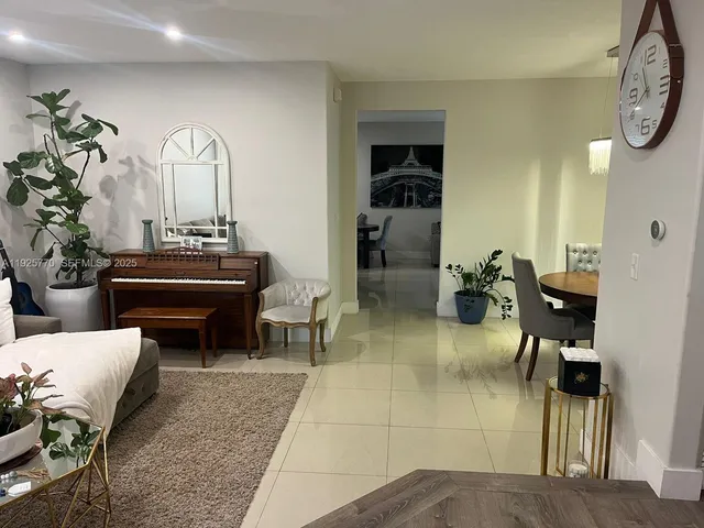 a living room with furniture a clock and a potted plant