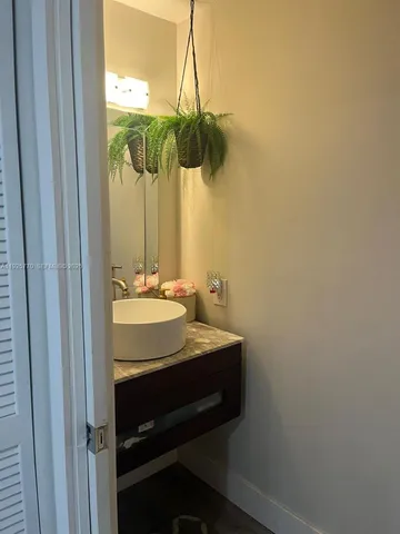 a bathroom with a sink a light fixture and a wooden floor