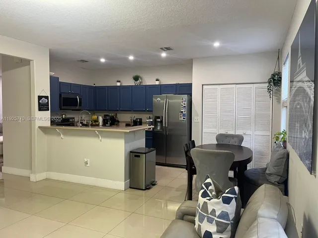 a kitchen with stainless steel appliances kitchen island granite countertop a refrigerator a stove a sink and a dining table with the view