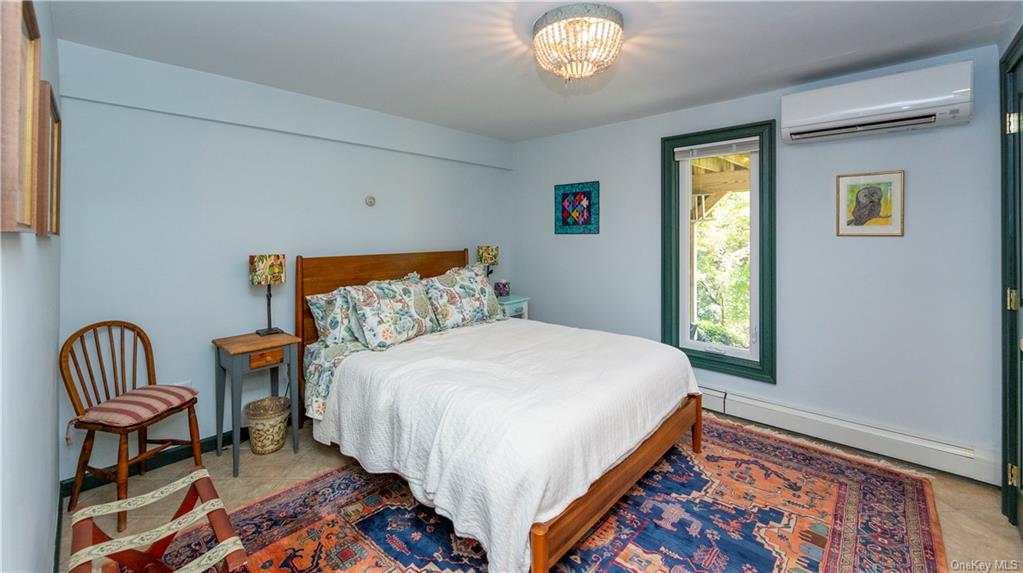 206 Quaker Hill Road Pawling, NY 12564 - Photo 34 of 36 Tiled bedroom featuring an AC wall unit, a chandelier, and a baseboard radiator