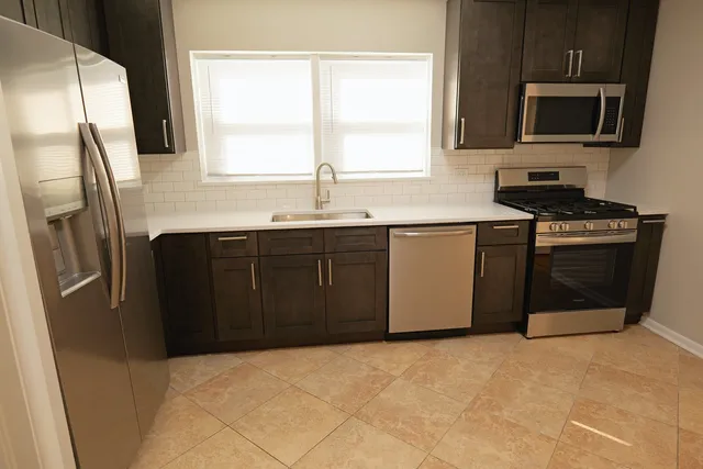 a kitchen with stainless steel appliances granite countertop a stove a sink and a microwave