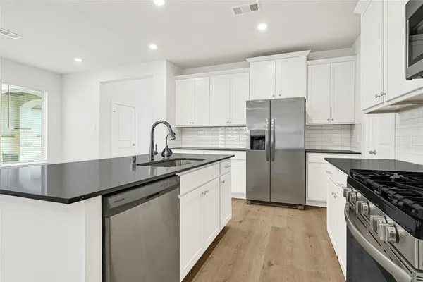 a kitchen with granite countertop a sink stove and refrigerator