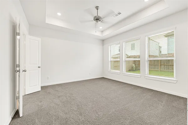 an empty room with windows and ceiling fan