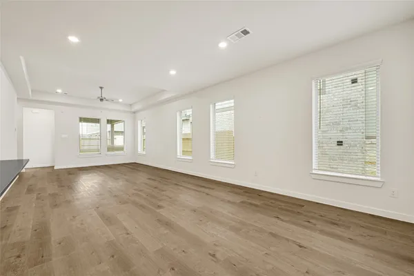 a view of an empty room with a window and wooden floor