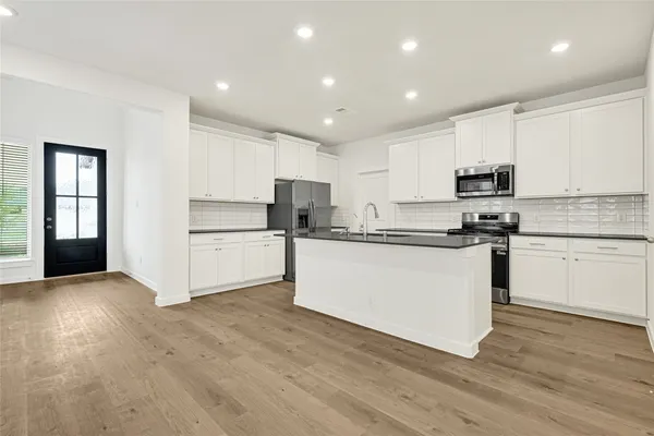 a kitchen with granite countertop white cabinets and stainless steel appliances
