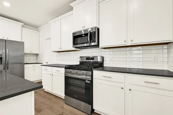 a kitchen with stainless steel appliances granite countertop white cabinets sink and stainless steel appliances