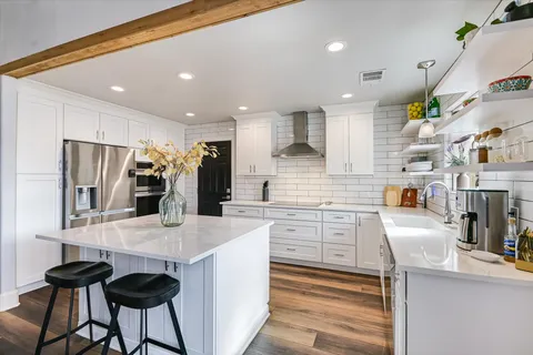a kitchen with stainless steel appliances granite countertop a sink refrigerator and cabinets