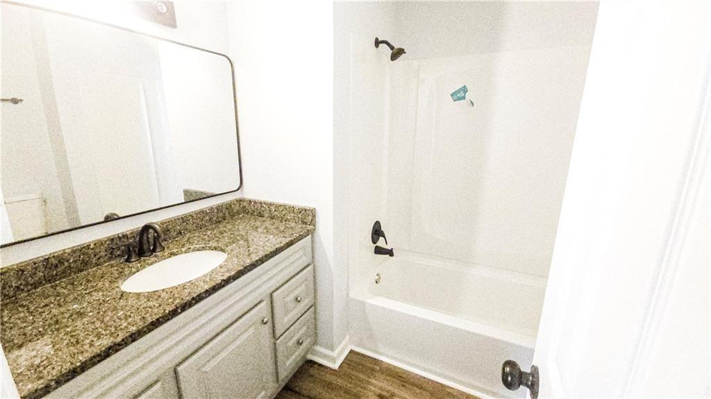 5582 Windwood Road Atlanta, GA 30349 - Photo 23 of 29 a bathroom with a granite countertop sink a mirror and a bathtub
