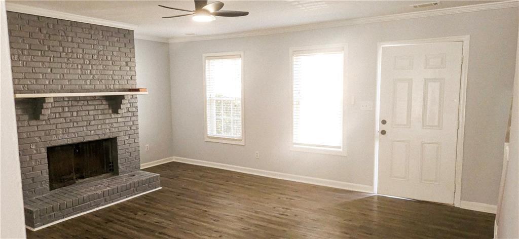 5582 Windwood Road Atlanta, GA 30349 - Photo 6 of 29 a view of an empty room with wooden floor fireplace and a window