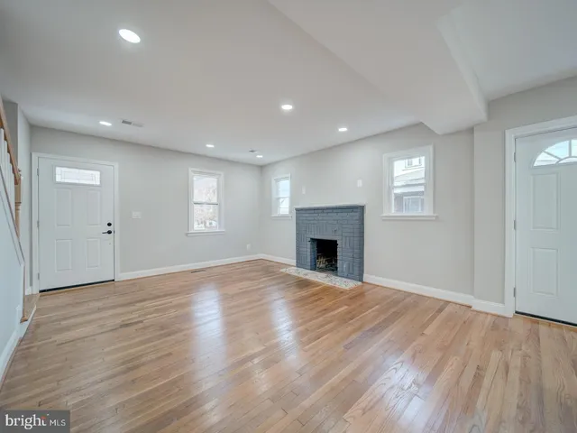 an empty room with windows and fireplace