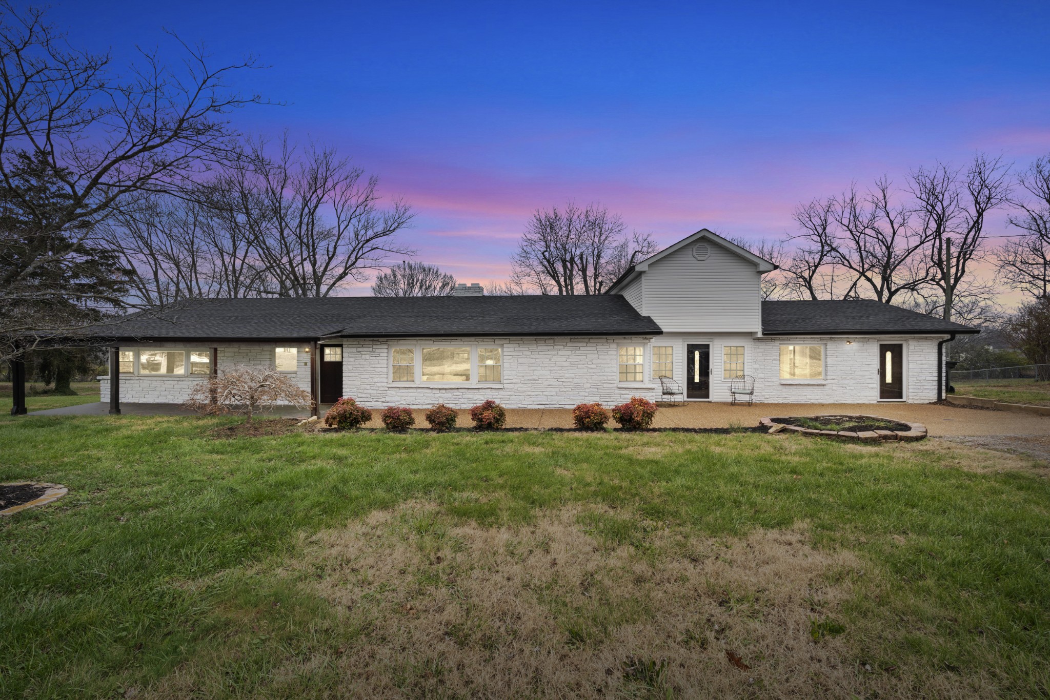 a front view of a house with a garden and trees