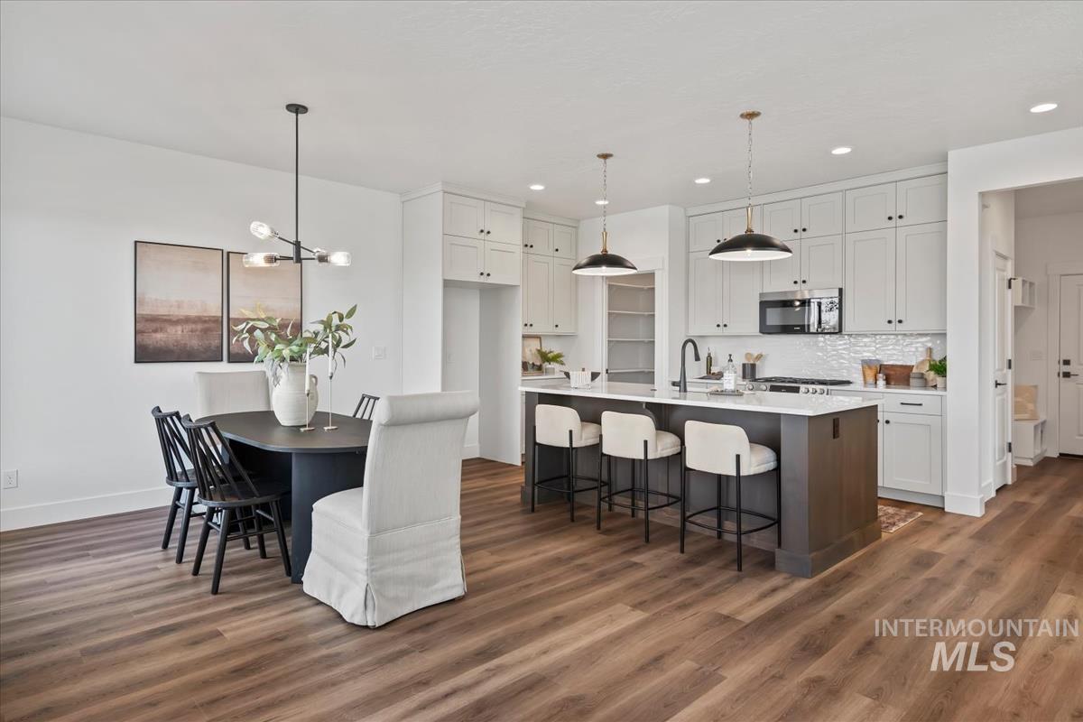 749 South Calhoun Lane Star, ID 83669 - Photo 17 of 34 Two tone kitchen with a kitchen breakfast bar, a kitchen island with sink, stainless steel microwave, dark wood-type flooring, and two tone color scheme