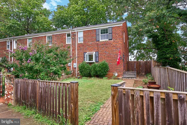 a view of a house with wooden fence next to a yard