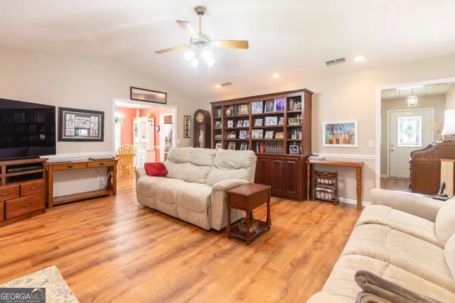 a living room with furniture a flat screen tv and a refrigerator