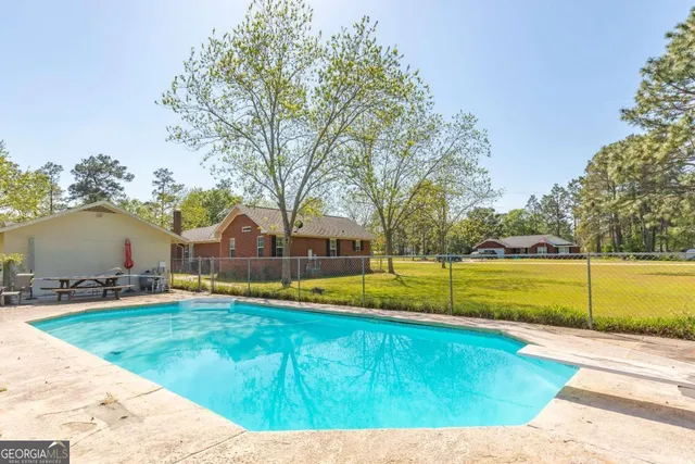 a front view of a house with swimming pool and large trees
