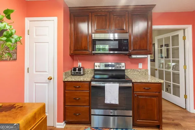 a kitchen with stainless steel appliances granite countertop a refrigerator a stove a sink dishwasher a dining table and chairs with wooden floor