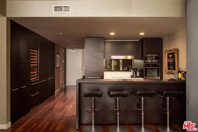 a kitchen with kitchen island granite countertop a table chairs refrigerator and microwave