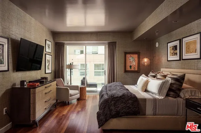 a bedroom with a bed and a flat tv screen on the dresser