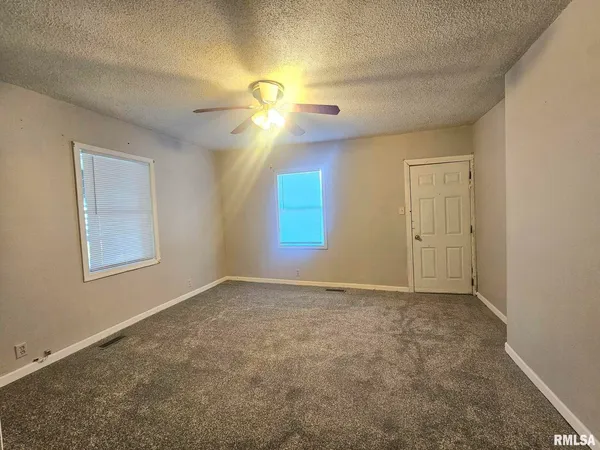 an empty room with windows and fan