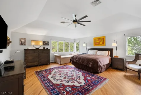 a spacious bedroom with a bed and wooden floor